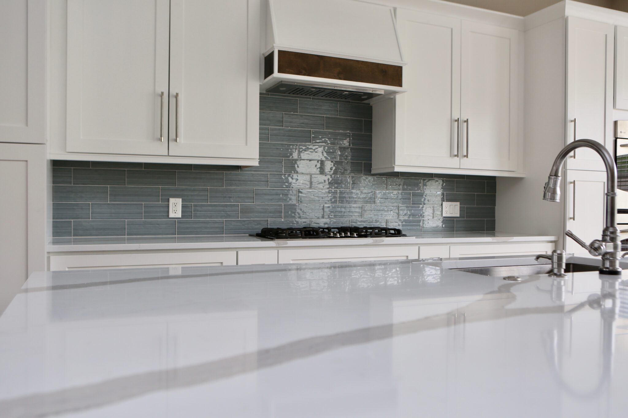 Modern kitchen with glossy white counters and tiled backsplash